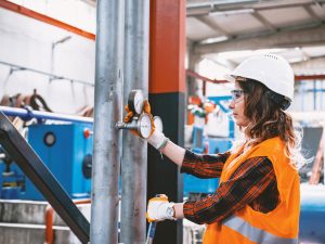 Portrait of young businesswoman working with ball valves in factory